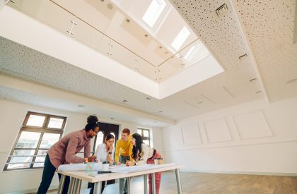 Professional multiracial team of male and female engineers or architects having a meeting and brainstorming together over a building project they are working on while gathered around the table.